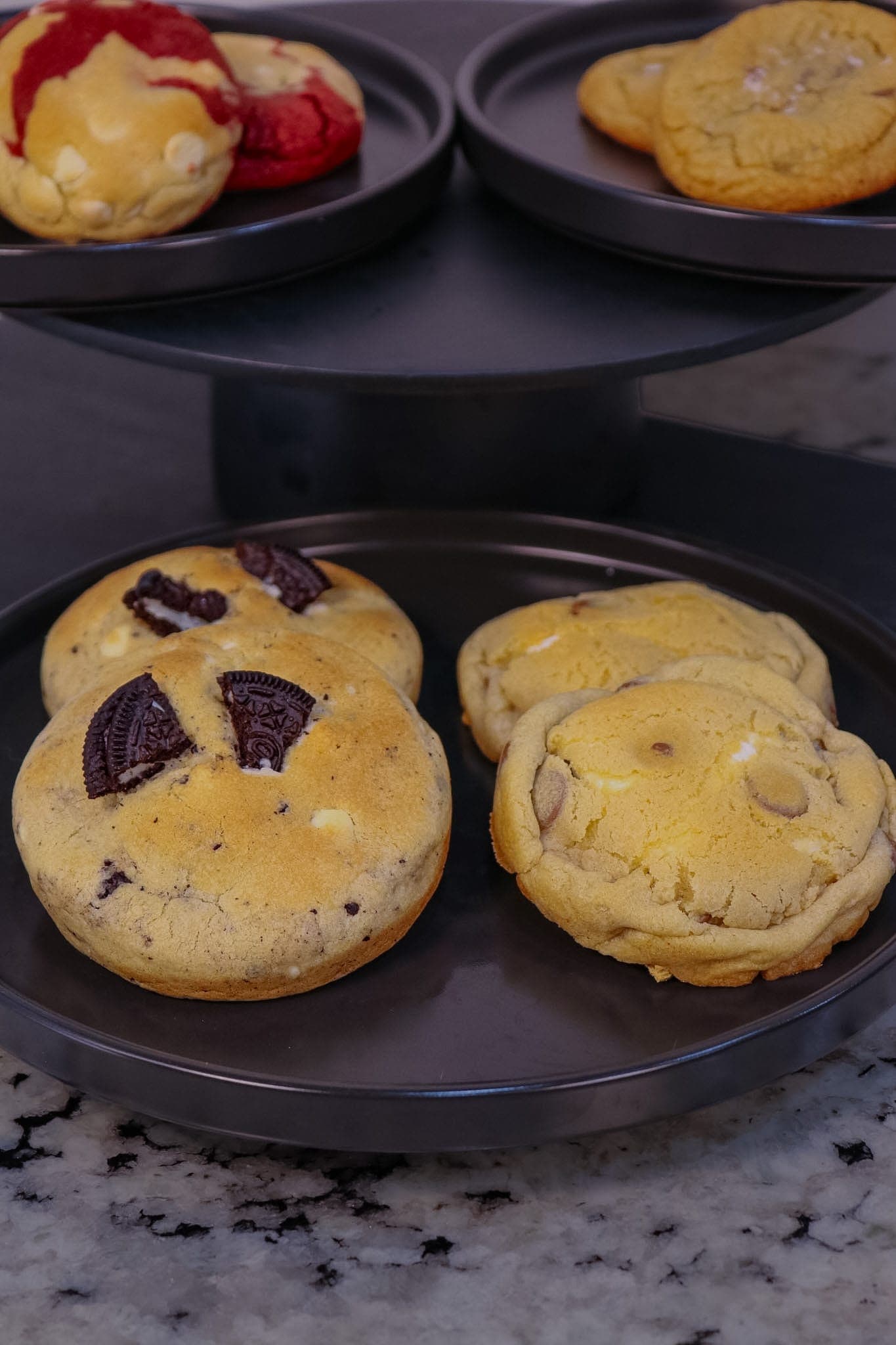 Tiered black plates of stuffed cookies on a granite counter