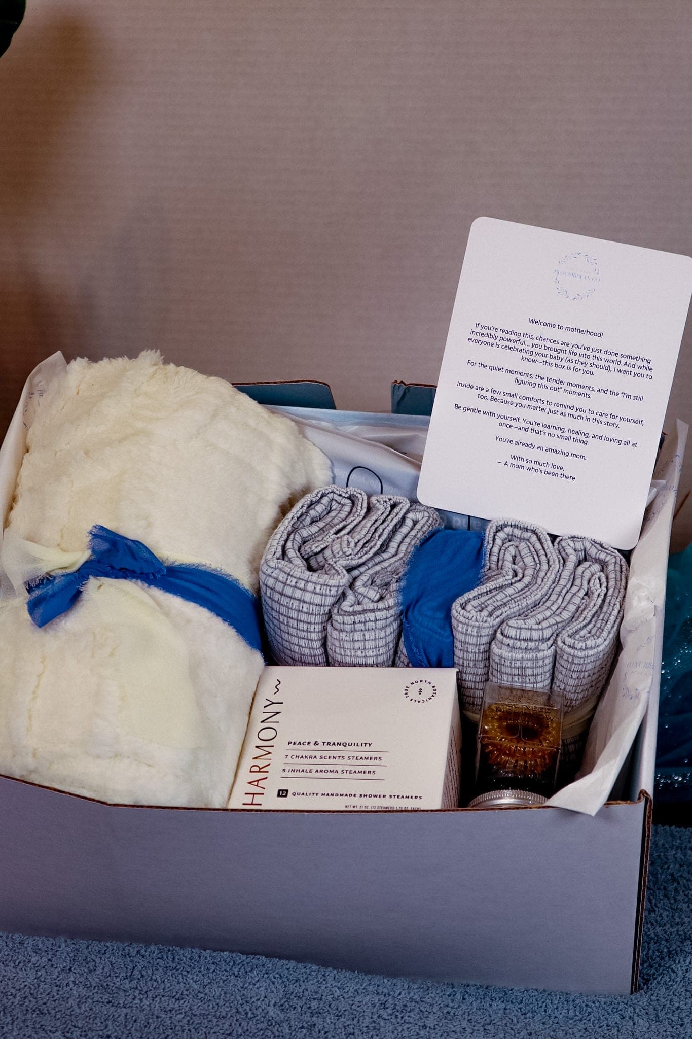 New-mother care box with a plush blanket, shower steamers, and a welcome-to-motherhood card