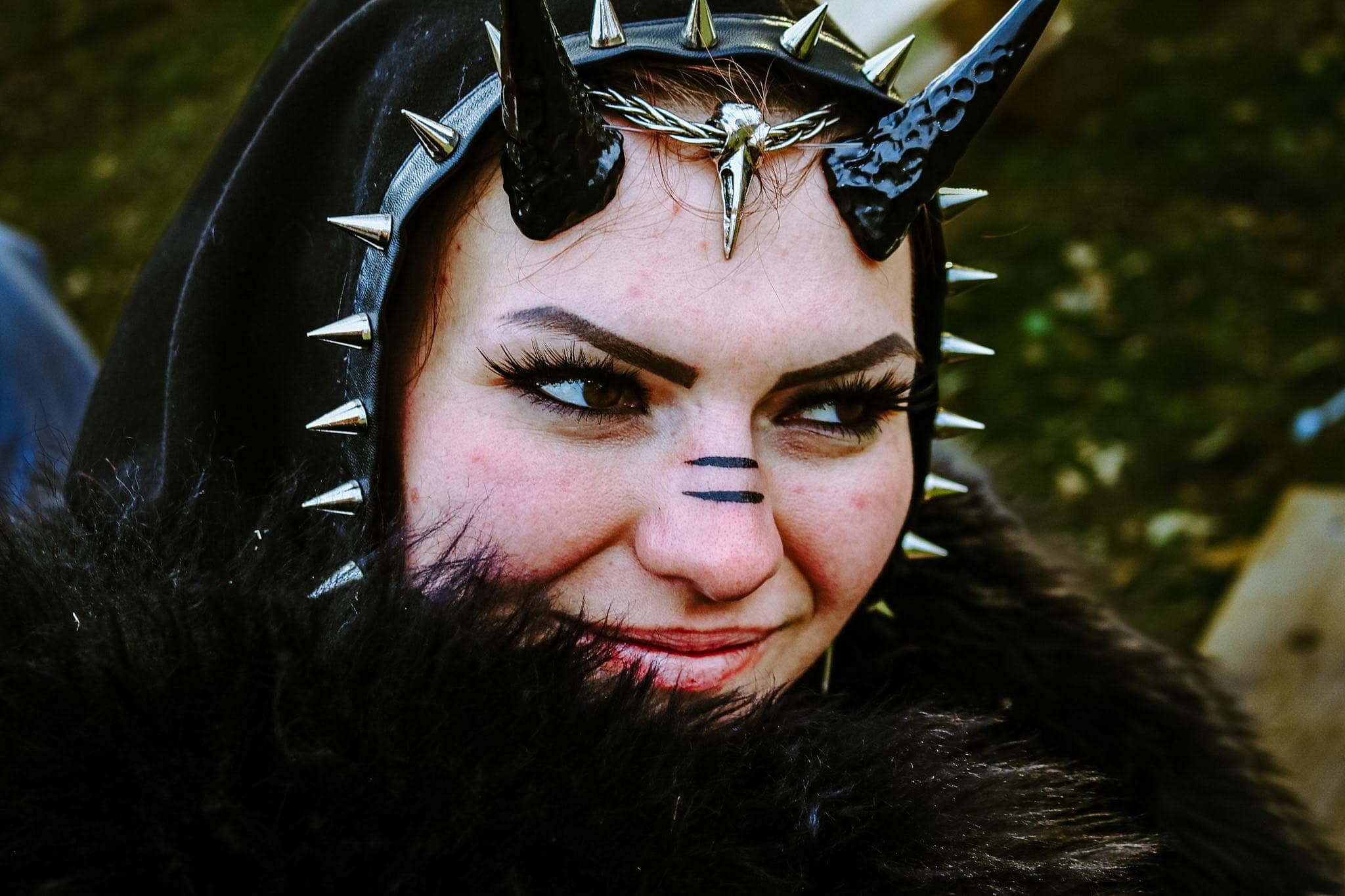 Close festival portrait in a spiked leather hood with black horns and a raven-skull circlet